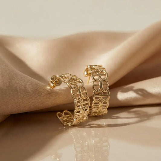 Gold hoop earrings on a beige fabric background