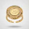 Gold ring with a coin design and gemstones on a light gray background