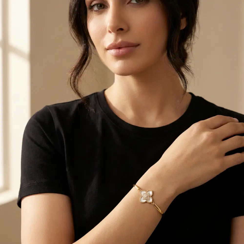 Woman wearing a gold bracelet with a floral design on her wrist.