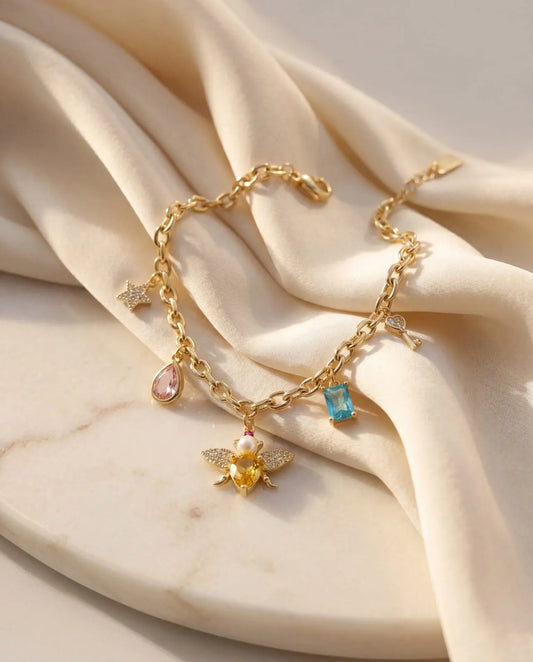 Elegant gold plated charm bracelet featuring a sparkling honey bee, vibrant colorful crystals, and delicate gold pendants from Bellora Bloom.