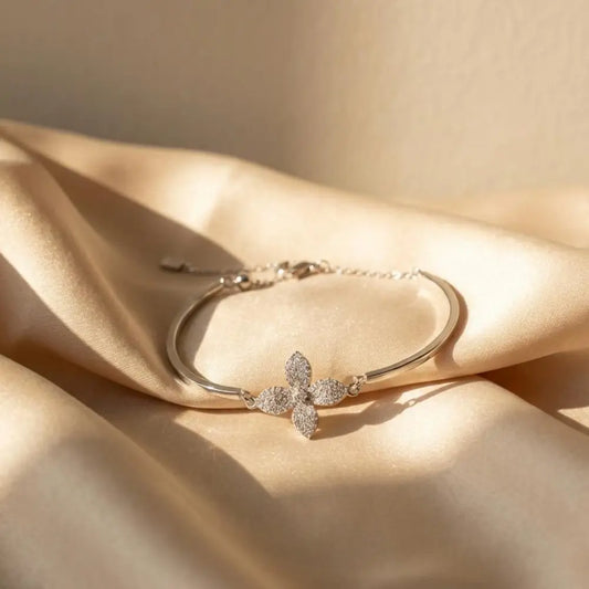 Silver bracelet with a floral clasp on beige fabric