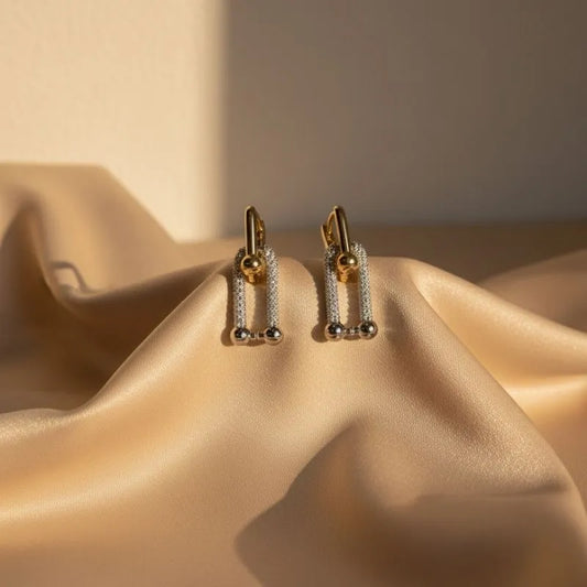 Gold earrings on a beige fabric surface