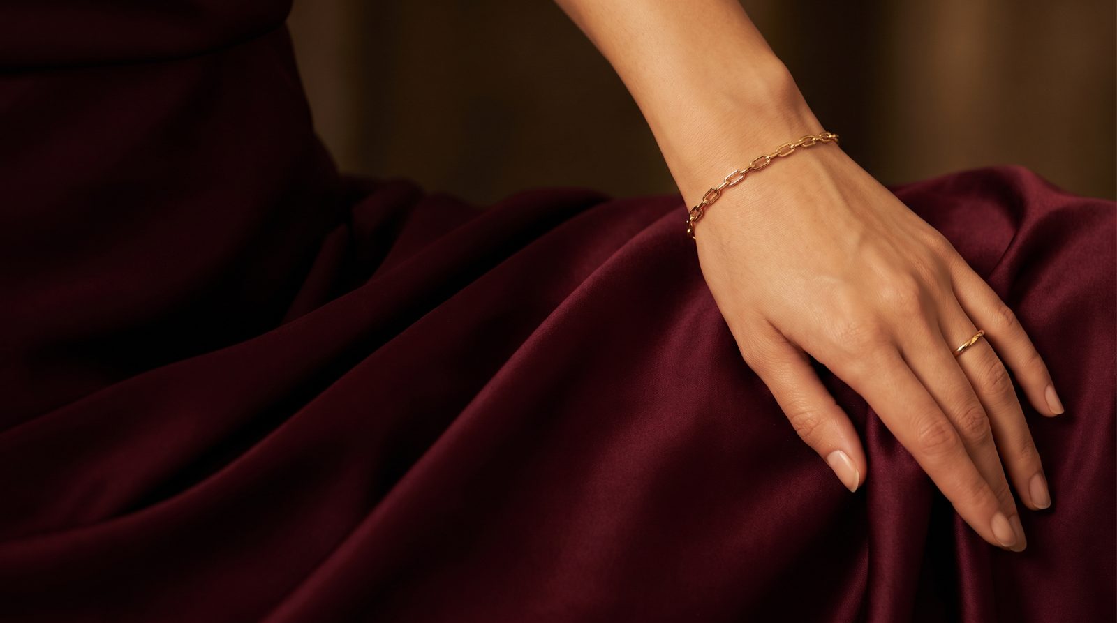 Gold plated bracelet worn over wine silk