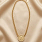 Gold plated statement necklace featuring a thick curb chain and a vintage engraved coin medallion framed with zircon crystals from Bellora Bloom.