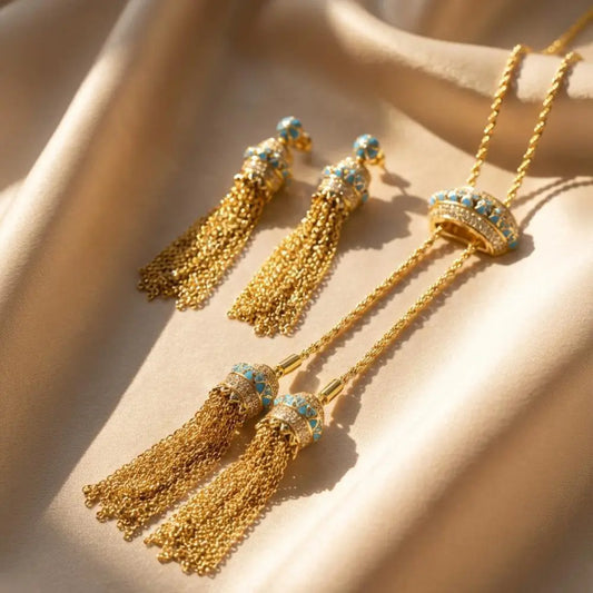 Gold tassel earrings with turquoise stones on a beige fabric background
