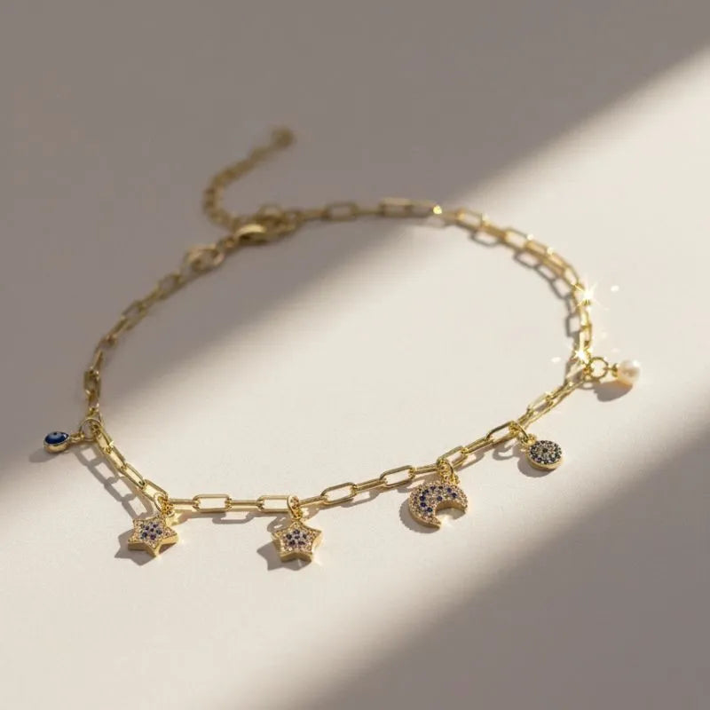 Gold-plated bracelet with star, moon, and eye pendants featuring blue and white crystals
