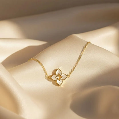 Gold bracelet with a floral pendant on a beige fabric background
