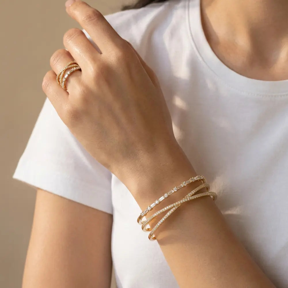 Close-up of a hand wearing gGold Plated Criss-Cross Baguette Bracelet and Ring Setbackground