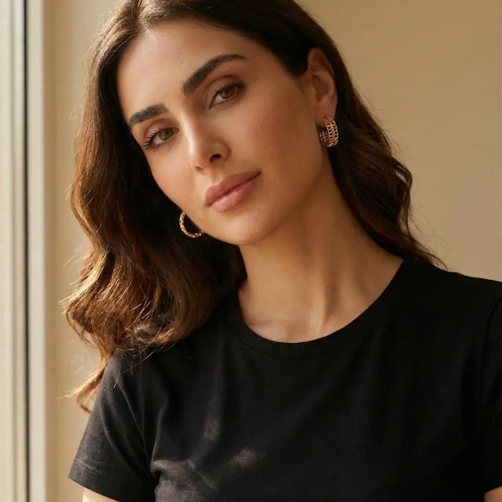Woman wearing gold hoop earrings against a neutral background