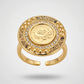 Gold ring with a coin design and gemstones on a light gray background