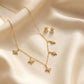 Close up of a luxury 18k gold plated necklace and matching stud earrings set featuring five sparkling star charms paved with clear zirconia on smooth satin.