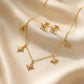 Close up of a luxury 18k gold plated necklace and matching stud earrings set featuring five sparkling star charms paved with clear zirconia on smooth satin.