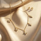 Close up of a luxury 18k gold plated necklace and matching stud earrings set featuring five sparkling star charms paved with clear zirconia on smooth satin.