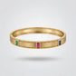 Gold bracelet with gemstones on a light gray background