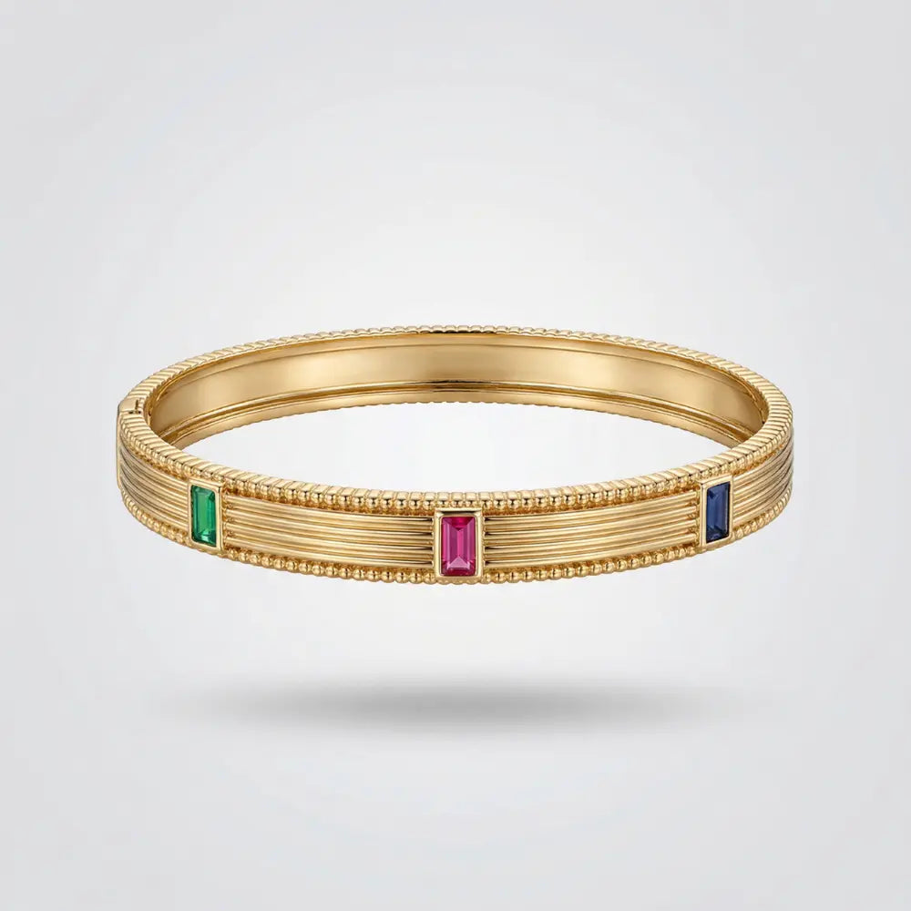 Gold bracelet with gemstones on a light gray background