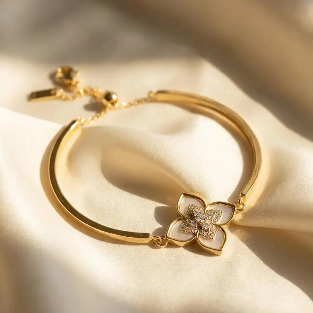 Gold bracelet with a floral clasp on a soft beige background