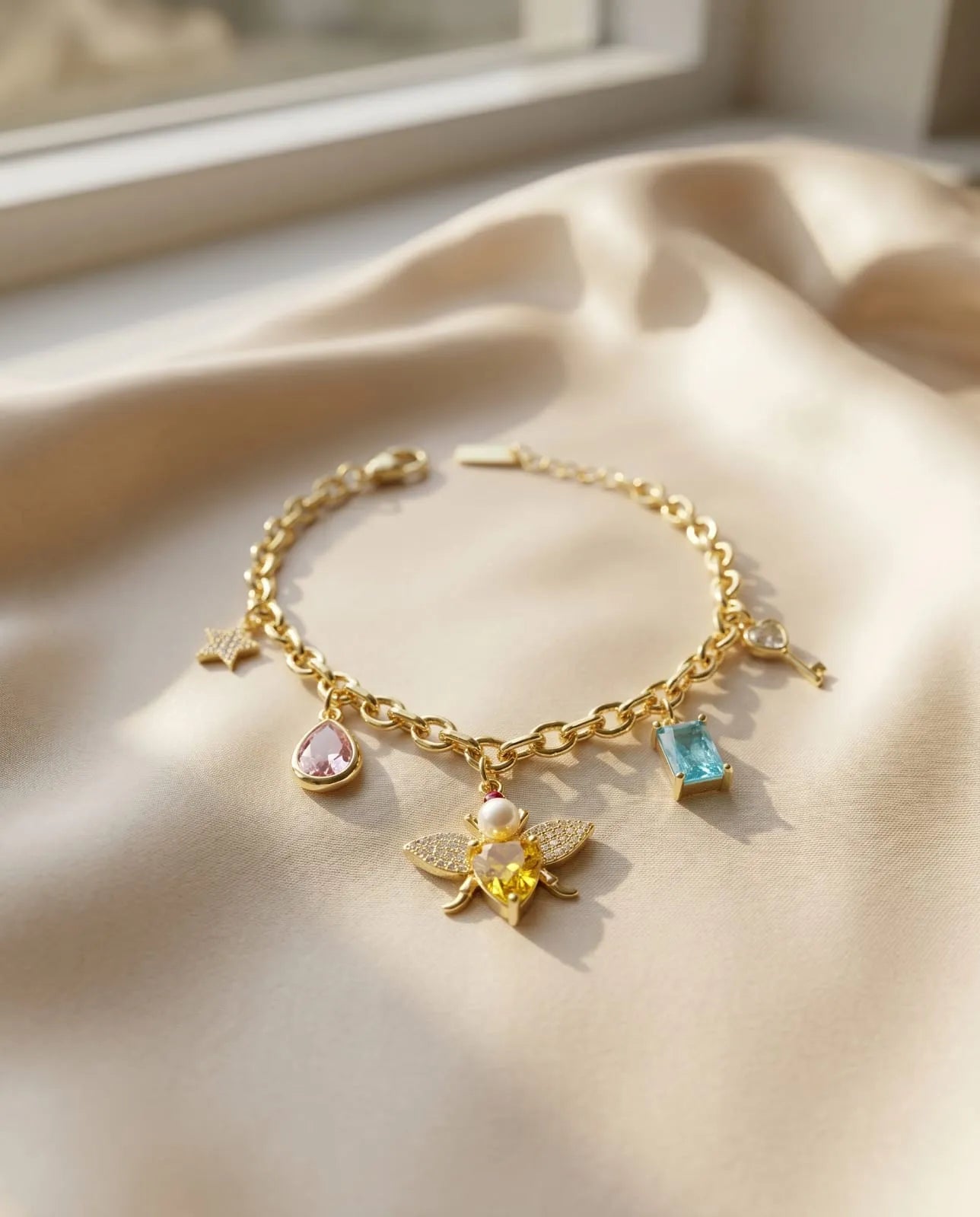 Elegant gold plated charm bracelet featuring a sparkling honey bee, vibrant colorful crystals, and delicate gold pendants from Bellora Bloom.