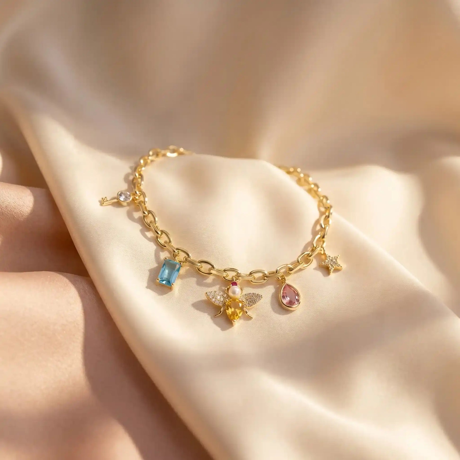 Elegant gold plated charm bracelet featuring a sparkling honey bee, vibrant colorful crystals, and delicate gold pendants from Bellora Bloom.