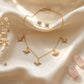 Close up of a luxury 18k gold plated necklace and matching stud earrings set featuring five sparkling star charms paved with clear zirconia on smooth satin.