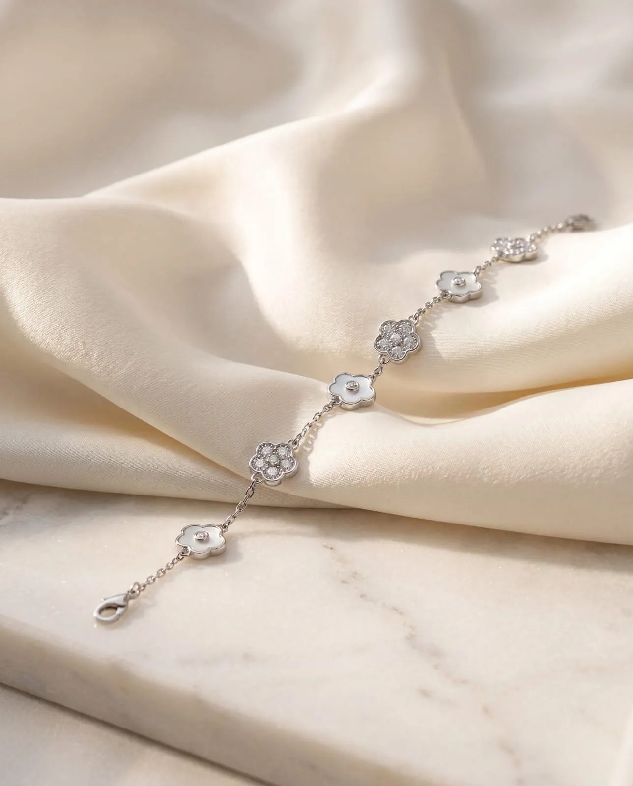 luxury silver alternating flower bracelet featuring sculpted white mother of pearl elements and brilliant cubic zirconia paved blossoms resting on elegant ivory satin.