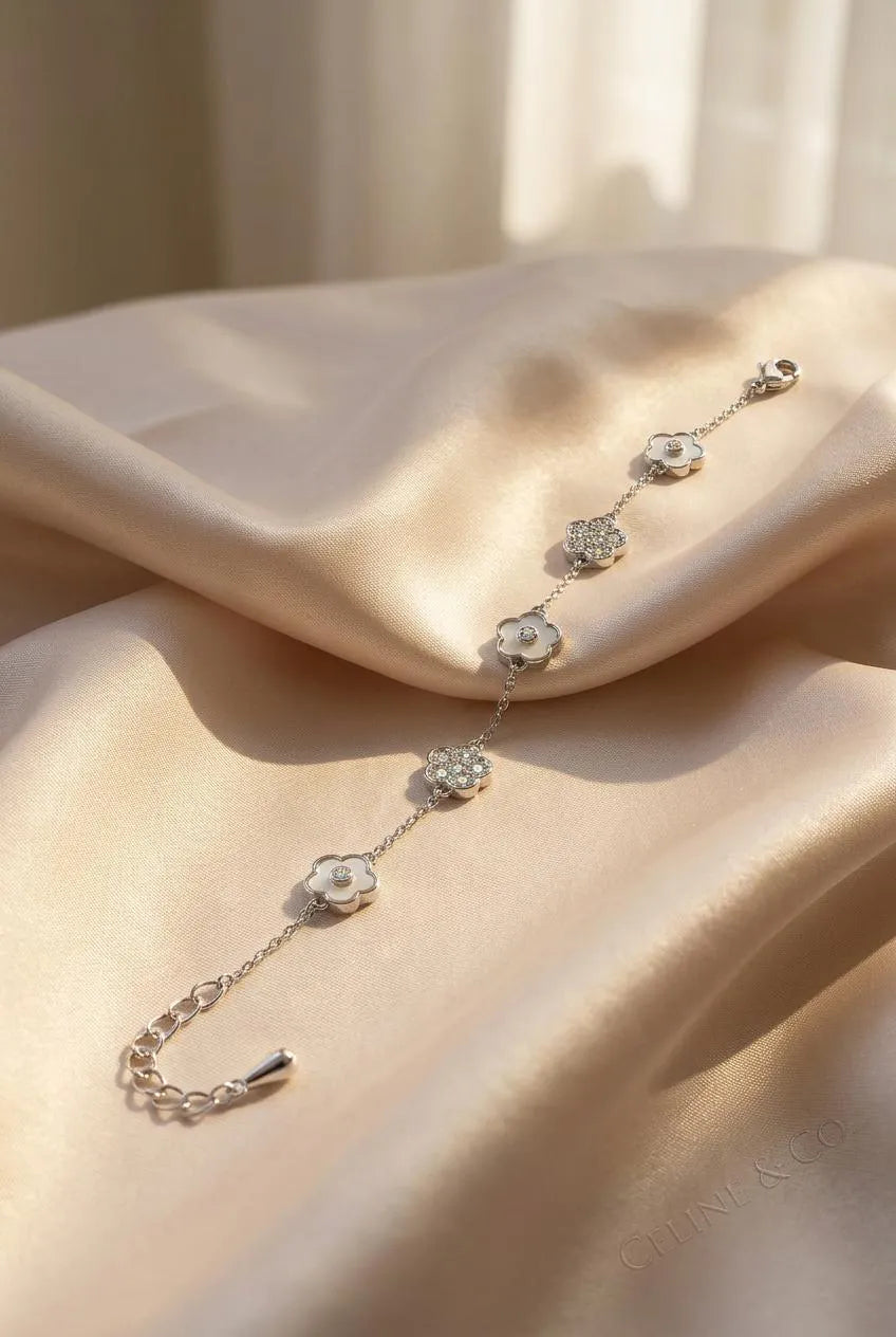 luxury silver alternating flower bracelet showcasing the rhythmic sequence of five petal blossoms, the lobster clasp, and the extension chain on a golden fabric background.