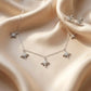 Close up of an elegant silver necklace and matching stud earrings set featuring five sparkling star charms paved with clear zirconia on soft ivory satin.