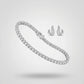 Silver tennis bracelet and curved stud earrings with baguette-cut diamonds on a neutral background.