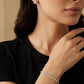 A woman wearing a delicate silver tennis bracelet and matching earrings, showcasing a classic minimalist look.